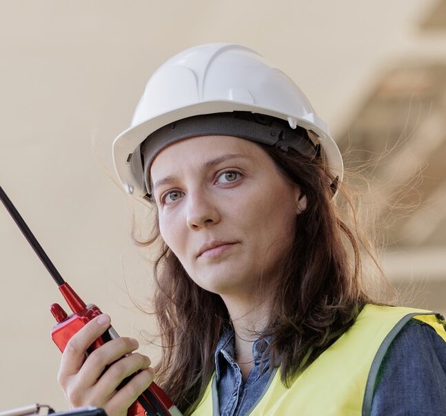 female engineer with a walkie-talkie at the construction site gives instructions. European